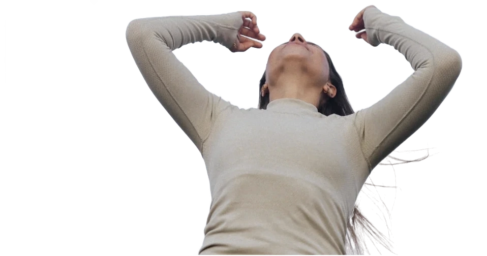 Frau im beigen Longsleeve, Arme erhoben, Blick in den Himmel